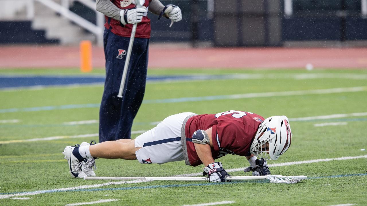 Penn defenseman Emmet Carroll performs a pushup as goalie Emmet Carroll stands watch during a March 9 game at Villanova.