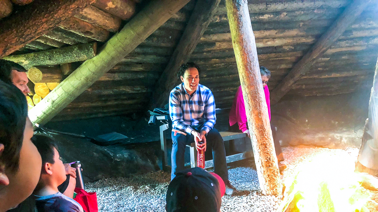 Allan Downey speaking with Indigenous youth fireside in a lodge